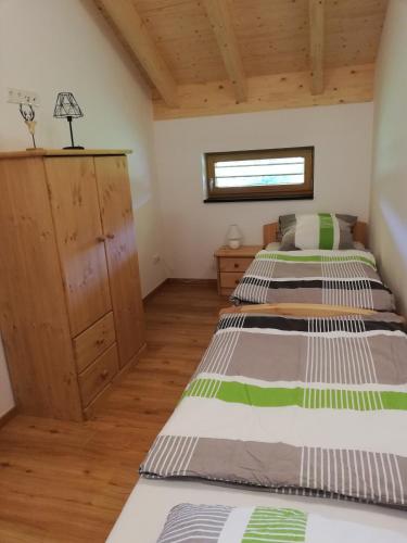 a bedroom with two beds and a wooden cabinet at Ferienhof Schmalzgrub in Böbrach