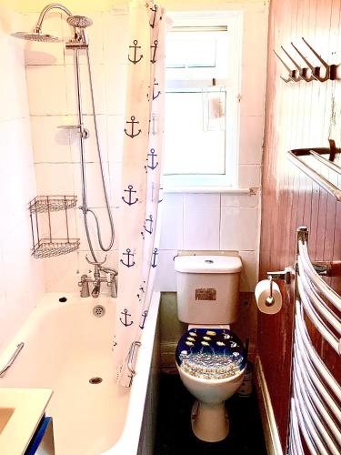 a bathroom with a toilet and a tub and a window at DEVON BEACH STATION in Paignton