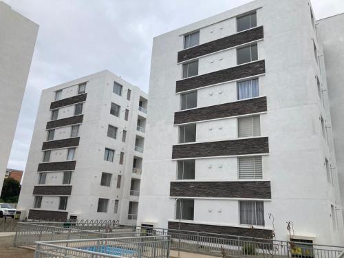 dos altos edificios blancos uno al lado del otro en Bonito y lindo departamento de vacaciones a metros de la Avenida del Mar, en La Serena