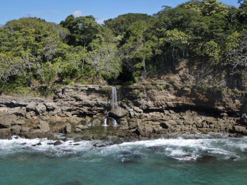 a waterfall on the side of a rocky beach at Tango Mar Beachfront Boutique Hotel & Villas in Tambor
