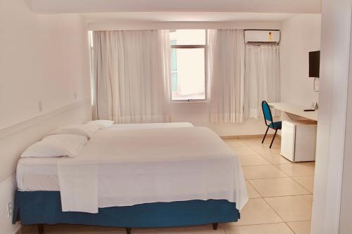ein weißes Schlafzimmer mit einem weißen Bett und einem Schreibtisch in der Unterkunft Praia Hotel Enseada in Maceió