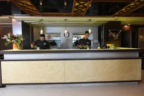 two men standing behind a bar in a restaurant at Kyriad Hotel Pimpri in Pune