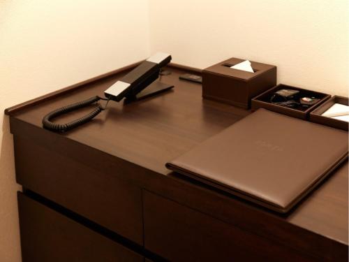 a desk with a phone and a laptop and a box at Hotel Forza Nagasaki in Nagasaki