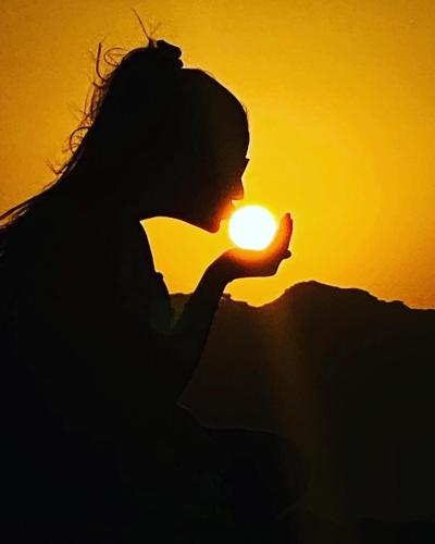 a silhouette of a woman holding the sun at sunset at Wadi Rum Moon Light Camp in Wadi Rum