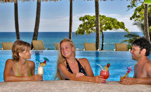 a group of people sitting in a pool with drinks at Tango Mar Beachfront Boutique Hotel & Villas in Tambor