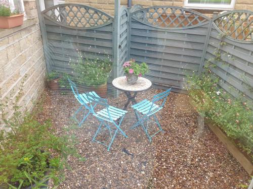 a patio with three chairs and a table in a yard at Horseshoe Forge Plover Cottage Lindley in Huddersfield