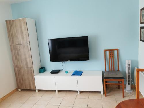 a white entertainment center with a flat screen tv on a blue wall at STUDIO 2 étoiles Rénové Proche des THERMES in Lamalou-les-Bains