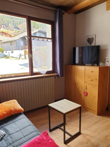 un salon avec un canapé, une table et une fenêtre dans l'établissement Le Si-près Pied des pistes, aux Carroz d'Arâches