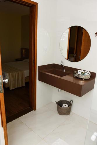 a bathroom with a sink and a mirror and a bed at Água Branca Park Hotel in Araçatuba