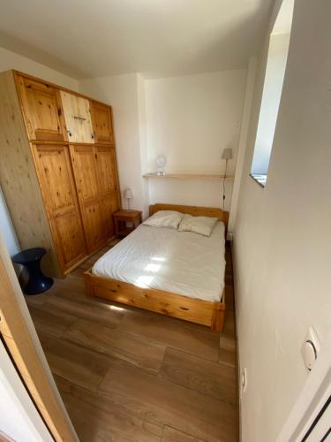 Habitación pequeña con cama y suelo de madera. en Appartement avec rez de jardin, Sauna et Hamam, en Villard-de-Lans
