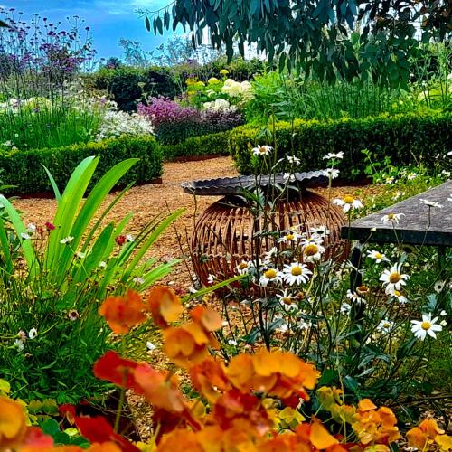 a garden with flowers and a table in the middle at The Oaks Glamping - Jasper's Shepherds Hut in Colkirk