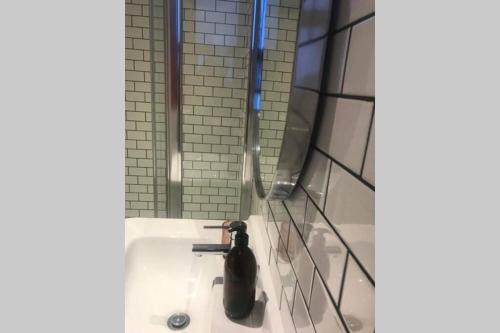 a bathroom with a shower with a black bottle on a sink at Luxurious Studio in the heart of Cape Town CBD in Cape Town