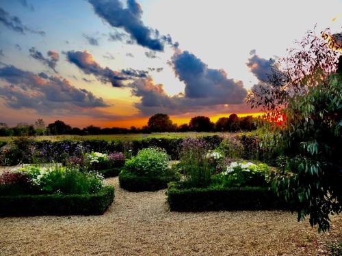 un jardín con flores y una puesta de sol en el fondo en The Oaks Glamping - Jasper's Shepherds Hut, en Colkirk