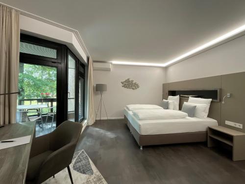 a hotel room with a bed and a desk and a window at Seehotel am Tankumsee in Isenbüttel