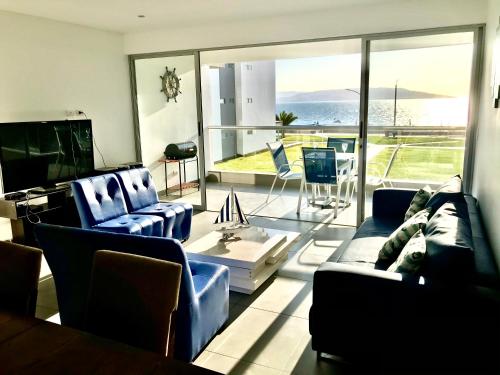 a living room with blue furniture and a large window at Paracas Paracas! 2do Piso Vista al Mar 140 Metros - Sotavento 201 T6 in Paracas