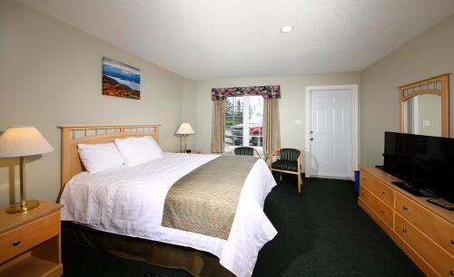 a bedroom with a bed and a flat screen tv at Fisherman's Landing Inn in Rocky Harbour