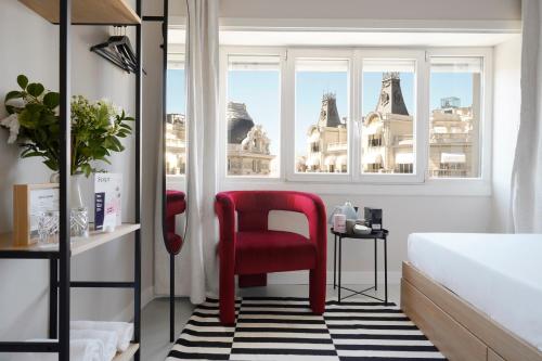 uma cadeira vermelha sentada num quarto com uma janela em numa I Script em Madri