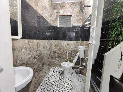 a bathroom with a toilet and a sink at Royal Wings Apartments in Mysore