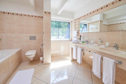 a bathroom with a tub and a toilet and a sink at Seehotel am Tankumsee in Isenbüttel
