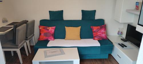 a room with a blue couch with colorful pillows at Apartments Plavčić in Plomin