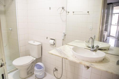a white bathroom with a sink and a toilet at Búzios Internacional Apart Hotel in Búzios