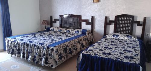 um quarto com 2 camas com lençóis azuis e brancos em hotel cote d'or m'diq em M'diq