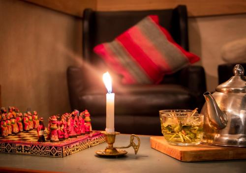 a candle on a table next to a tea pot and a candle at Nao Victoria Hostel in Cusco