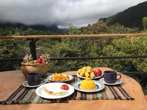 uma mesa com pratos de fruta e chávenas em Entre Montanhas Capão em Vale do Capão