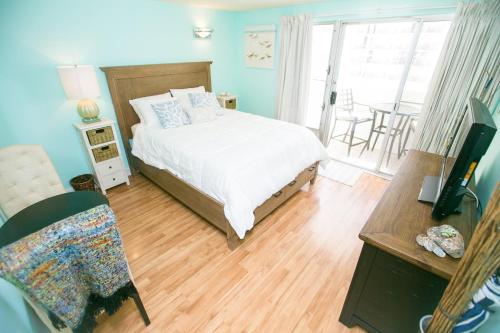 1 dormitorio con 1 cama y escritorio con TV en Kuhio Village 806, en Honolulu