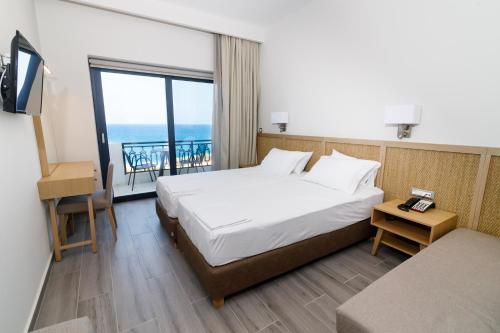 a hotel room with a bed and a view of the ocean at Elegant Beach Hotel - former Hotel Tsolaridis in Kyparissia