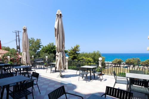a patio with tables and chairs and umbrellas at Elegant Beach Hotel in Kyparissia
