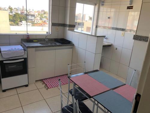 uma pequena cozinha com uma mesa e um lavatório em Apartamento com varanda em Lavras