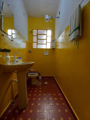 a yellow bathroom with a sink and a toilet at Infinito House - Casa inteira in São Paulo
