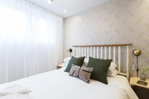 a bedroom with a white bed with green pillows at Serene and Styled Little Italy Studio full bath by Den Stays in Montréal