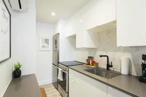a kitchen with white cabinets and a sink at Serene and Styled Little Italy Studio full bath by Den Stays in Montréal