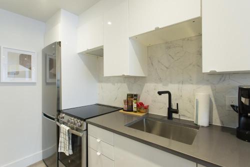 a kitchen with white cabinets and a sink at Serene and Styled Little Italy Studio full bath by Den Stays in Montréal