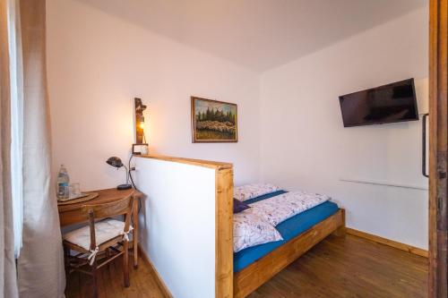 a bedroom with a bed and a desk and a television at Villa Theresienhof in Rosegg