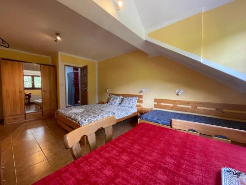 a bedroom with two beds and a red rug at Chata Ramzovské sedlo in Ramzová