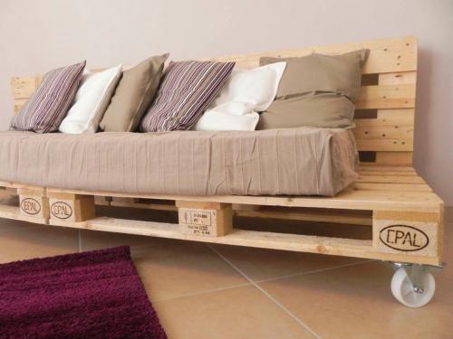 uma cama num carrinho de madeira com almofadas em La Casa di Milly em Alba