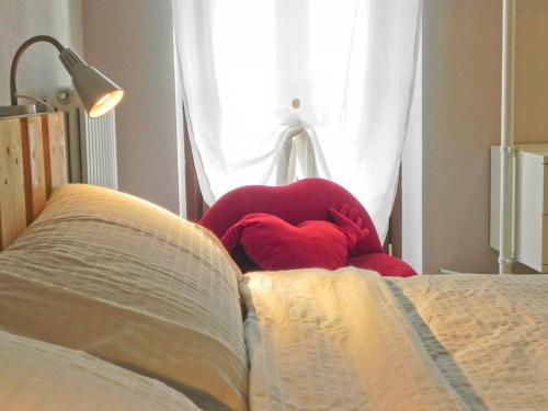 a red chair sitting on a bed next to a book at La Casa di Milly in Alba