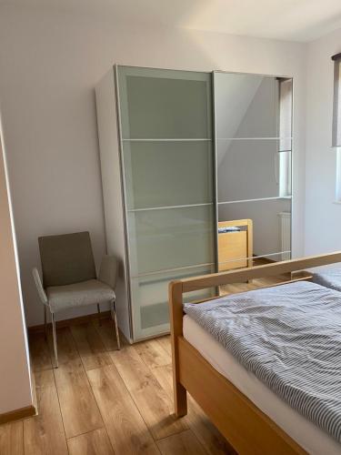 a bedroom with a bed and a chair at Lesny Apartament in Ostrzyce