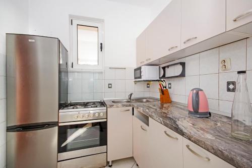 a kitchen with a stainless steel refrigerator and white cabinets at Apartmani ANDRIJA in Živogošće