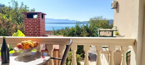 a balcony with a glass of wine and a bowl of fruit at Apartmani ANDRIJA in Živogošće
