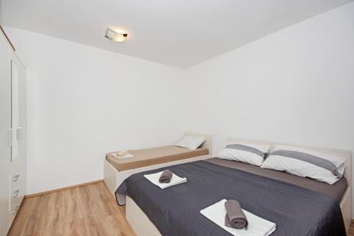 a white room with a bed with towels on it at Apartmani ANDRIJA in Živogošće