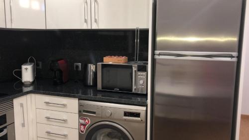 a kitchen with a stainless steel refrigerator and a microwave at Casas do Baleeiro - Whaler's Houses in Caniçal