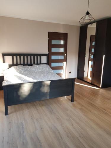 a large bed in a room with a wooden floor at Apartament Wydminy in Wydminy