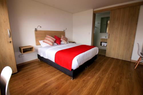 a bedroom with a large bed with red and white pillows at Normandía Tower in Bogotá