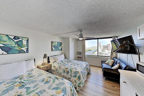a bedroom with two beds and a couch and a window at Hawaiian Monarch 2108 condo in Honolulu