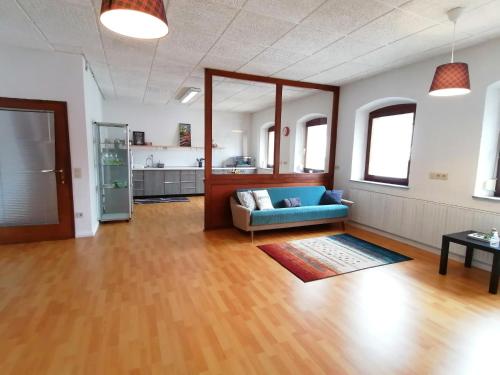 Geräumige Wohnung in zentraler Lage في Emskirchen: غرفة معيشة مع أريكة زرقاء ومطبخ