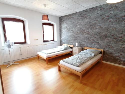 Geräumige Wohnung in zentraler Lage في Emskirchen: سريرين في غرفة بجدار حجري